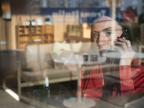 Reflective window showing woman on phone, blending indoor and outdoor scenes