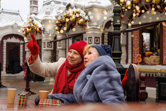 Excited senior friends in outdoor Christmas market holidays. Diversity, happy and elderly people in retirement enjoying holidays.