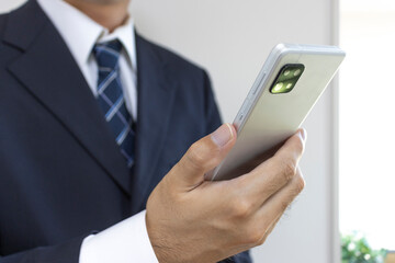 スーツを着てスマートフォンを持つ男の手（30代、日本人）