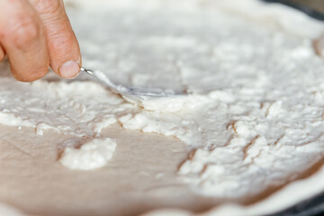 making pizza cooking at home spreading souse cream cheese on a dough
