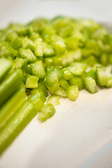 close-up of chopped up fresh celery in a pile against an off-white cutting board with copy space available