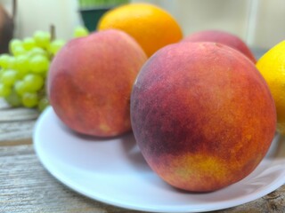 peaches on a plate surrounded by other fruits. high-quality photo