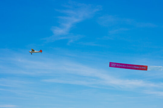 Rio de Janeiro, RJ, Brazil, February 11, 2024: Old vintage retro propeller engine airplane flying with advertiser banner over the beach in Rio de Janeiro