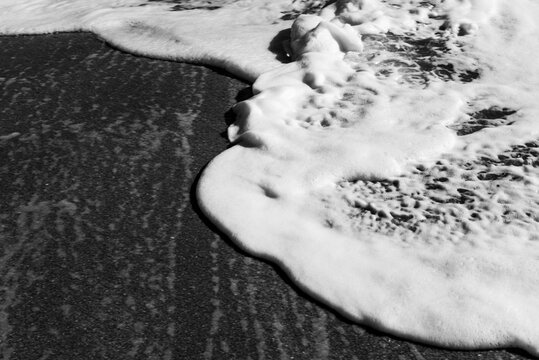 Black and white study of foamy waves overlapping on a beach on Hutchinson Island, Florida