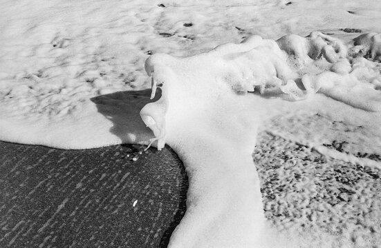 Black and white study of foamy waves overlapping on a beach on Hutchinson Island, Florida