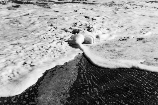 Black and white study of foamy waves overlapping on a beach on Hutchinson Island, Florida