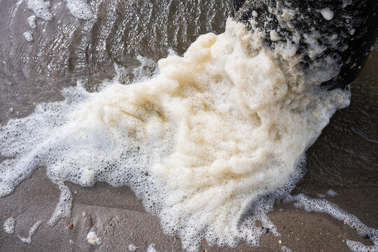 Sea foam piled up against the pylon of a pier on Oak Island, North Carolina in winter