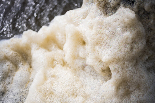 Detail of sea foam piled up against the pylon of a pier on Oak Island, North Carolina in winter