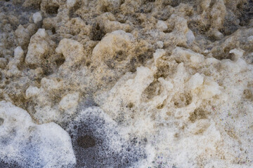 Closeup detail of sea foam along the beach of Oak Island, North Carolina in winter