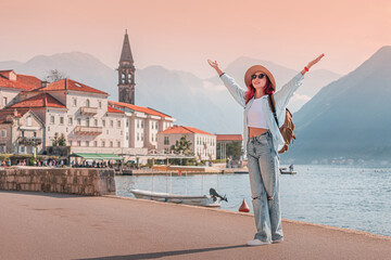Young woman with backpack enjoying the beautiful view of Perast town in the bay of Kotor, Montenegro