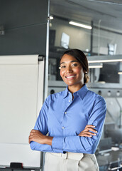 Happy confident young professional business woman corporate leader standing in office near whiteboard, smiling female African American businesswoman project manager business coach, vertical portrait.