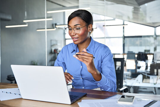 Professional young African American business woman hr manager team leader executive wearing blue shirt working in office looking at laptop having video conference call virtual online meeting. - Powered by Adobe