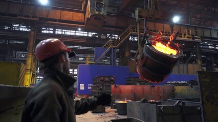 A diligent worker is overseeing the pouring of molten metal in a busy industrial facility. Stock Clip
