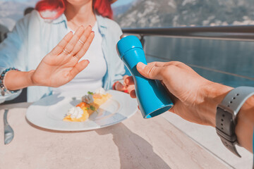 Woman refusing salt while having breakfast at restaurant by the sea