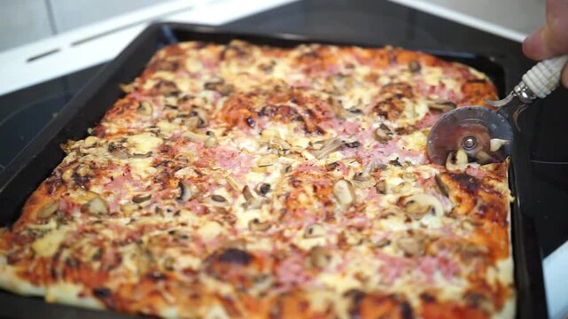 Woman's hand cutting pizza with pizza cutter wheel