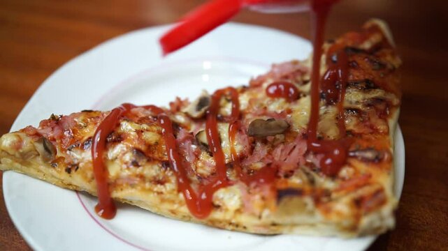 Close up of putting ketchup on a pizza slice