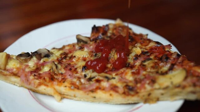 Close up of putting ketchup on a pizza slice