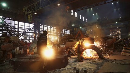 Workers toiling diligently in a Steel Mill surrounded by molten metal and an industrial atmosphere. Stock Clip