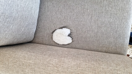 Damaged beige sofa in the living room, trace of a hot iron. You can't iron on the sofa. A heart...