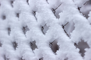 Snow on a chain-link fence. Blurred background, Winter concept