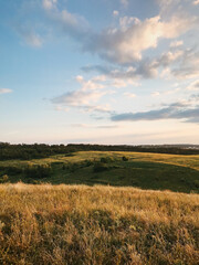 Sunset over hilly countryside. Lots of small clouds in the sky. Mid-summer rural scenery at dusk.