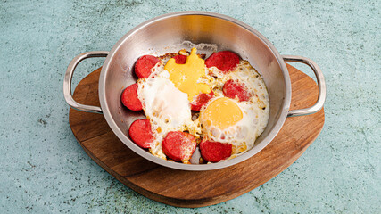 Fried eggs and sausages in pan for breakfast