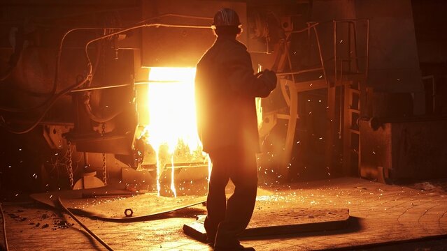 A dedicated workers silhouette stands out in the vibrant atmosphere of a steel mill. Stock Clip