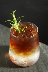 Refreshing espresso tonic drink with rosemary on dark table