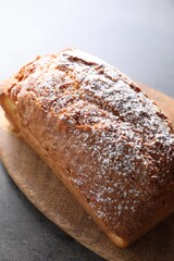 Tasty sponge cake with powdered sugar on grey table, closeup