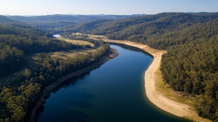 Obraz premium Wide-angle view captures a serene forest bordering a vibrant turquoise lake, with a sandy beach beckoning visitors to enjoy nature's beauty and tranquility