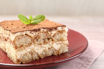 Delicious tiramisu with mint on light wooden table, closeup