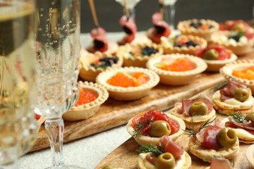 Many different tasty canapes and wine on white table, closeup