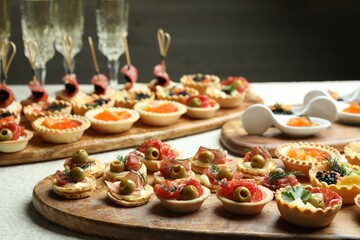 Many different tasty canapes and wine on white table