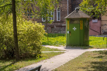 Historyczna toaleta (z napisem TOILET) w parku zamykana na kłódkę. Park pomiędzy zabytkowymi ceglanymi budynkami mieszkalnymi (historyczne kamienice - stare kamienice). © Grzegorz