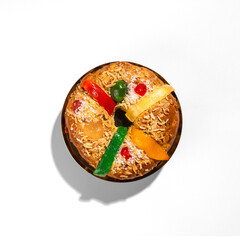 Overhead view of a traditional Portuguese Bolo Rei (King Cake) with vibrant candied fruits, almonds, and sugar on a white background. A festive dessert perfect for Christmas celebrations.