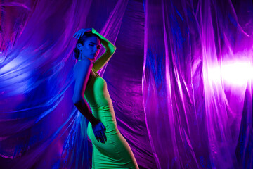 Photo of pretty model girl posing empty space green dress isolated on neon studio curtain background