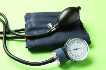 Blood pressure measuring device on green background, closeup
