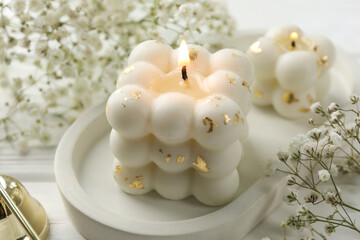 Stylish bubble candles and gypsophila flowers on white wooden table, closeup