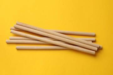 Bamboo drinking straws on yellow background, top view