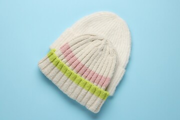 Warm woolen hats on light blue background, top view