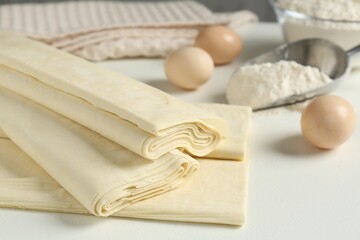 Raw puff pastry dough on white table, closeup