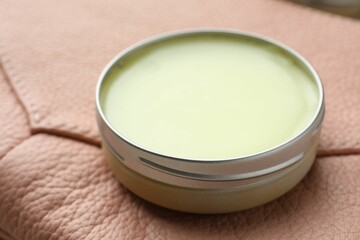 Natural solid perfume in container on leather surface, closeup