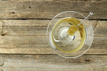 Martini cocktail with olives in glass on wooden table, top view. Space for text