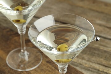 Martini cocktail with olives in glasses on wooden table, closeup