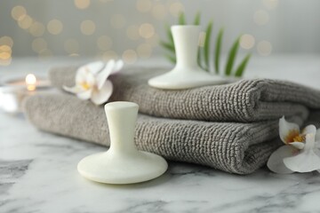Spa stones, orchid flowers, towels and leaf on white marble table, closeup