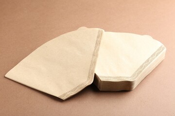 Paper coffee filters on brown background, closeup
