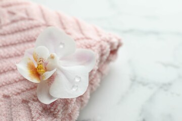 Orchid flower and towel on white marble table, closeup. Space for text