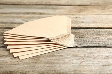 Many paper coffee filters on wooden table, space for text