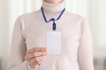Woman with blank badge indoors, closeup view
