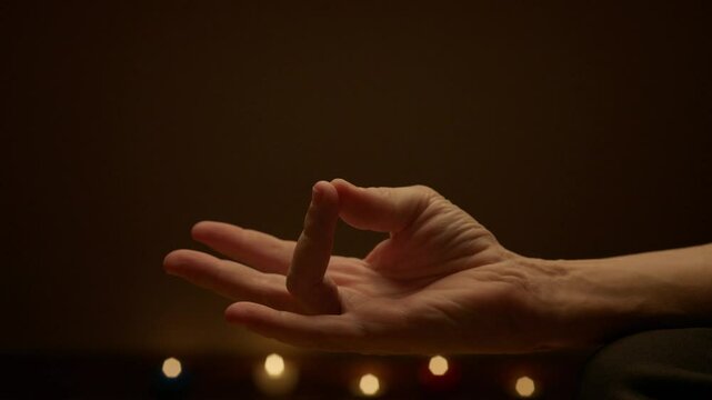 Closeup of A peaceful person meditating on a yoga mat with hands in a mudra gesture. Lit candles and a softly lit background evoke a calming atmosphere, perfect for yoga, meditation, and relaxation.
